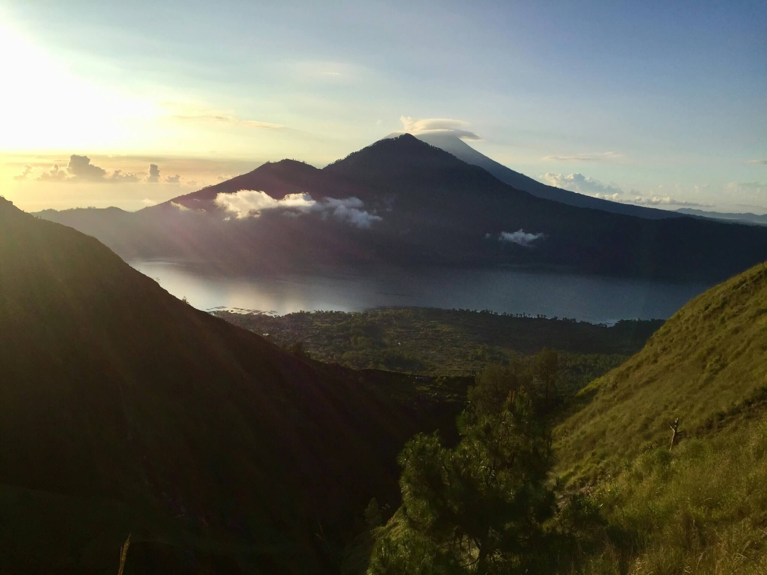 Stunning sunrise view of Mount Batur in Kintamani, Bali, with lush landscapes and a serene lake.