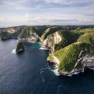 Drone shot of lush green cliffs and turquoise ocean at Nusa Penida in Bali, Indonesia.