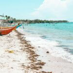 Serene tropical beach with traditional boats, inviting turquoise seawater and soft sandy shore.