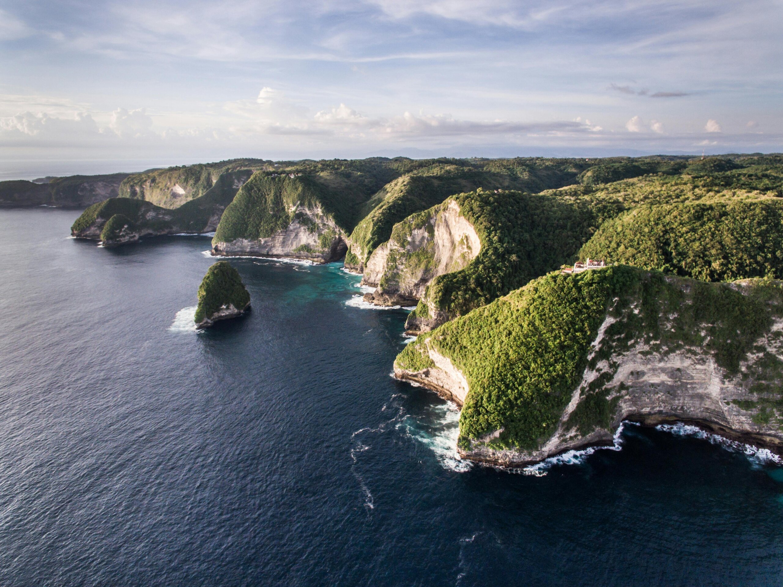 Drone shot of lush green cliffs and turquoise ocean at Nusa Penida in Bali, Indonesia.